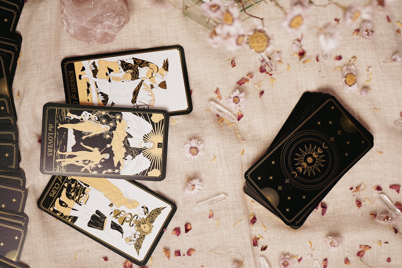 Flat lay of tarot cards on a fabric with flowers, crystals, and artistic details.